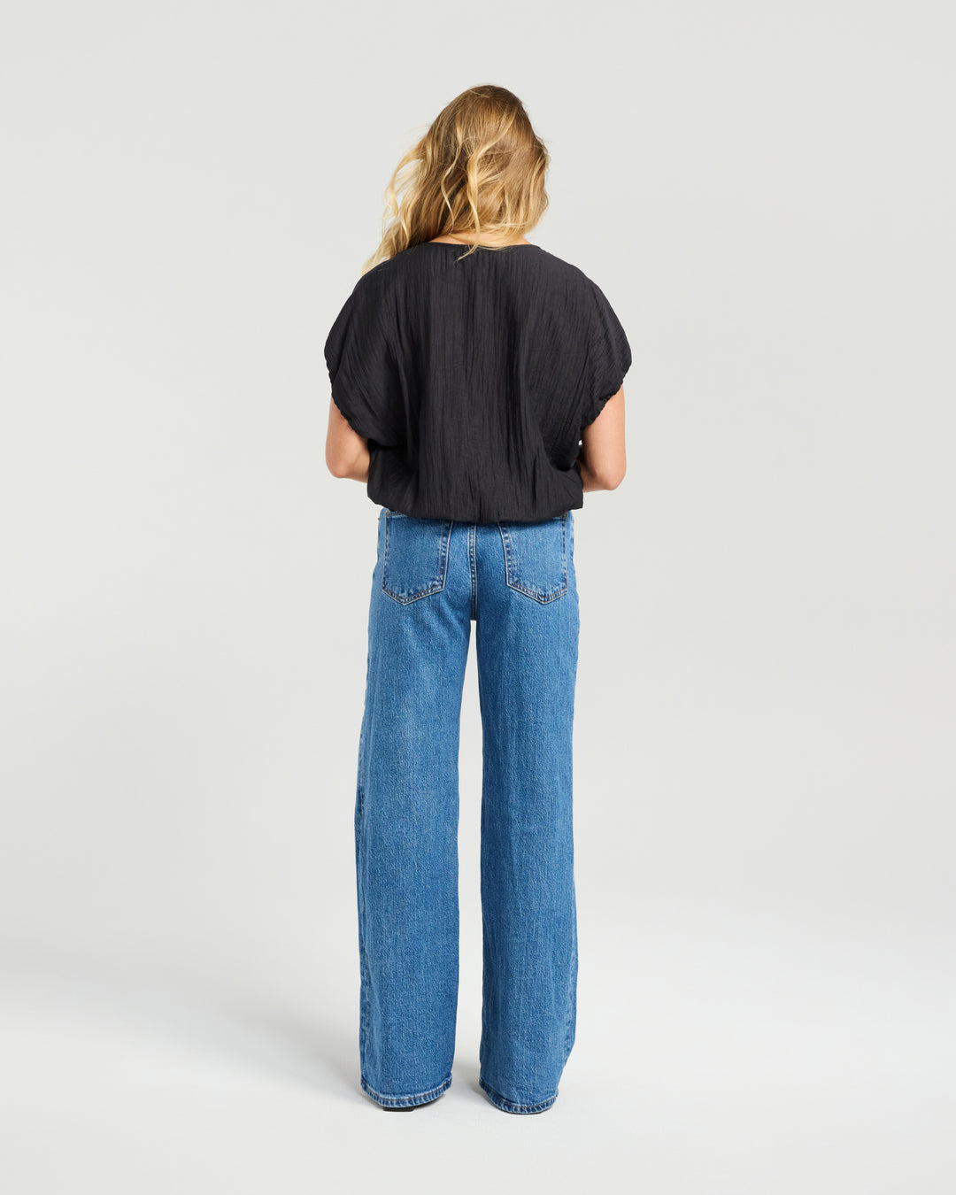 Back view of Kiwi Country Black Fern Top styled with wide-leg blue jeans.
