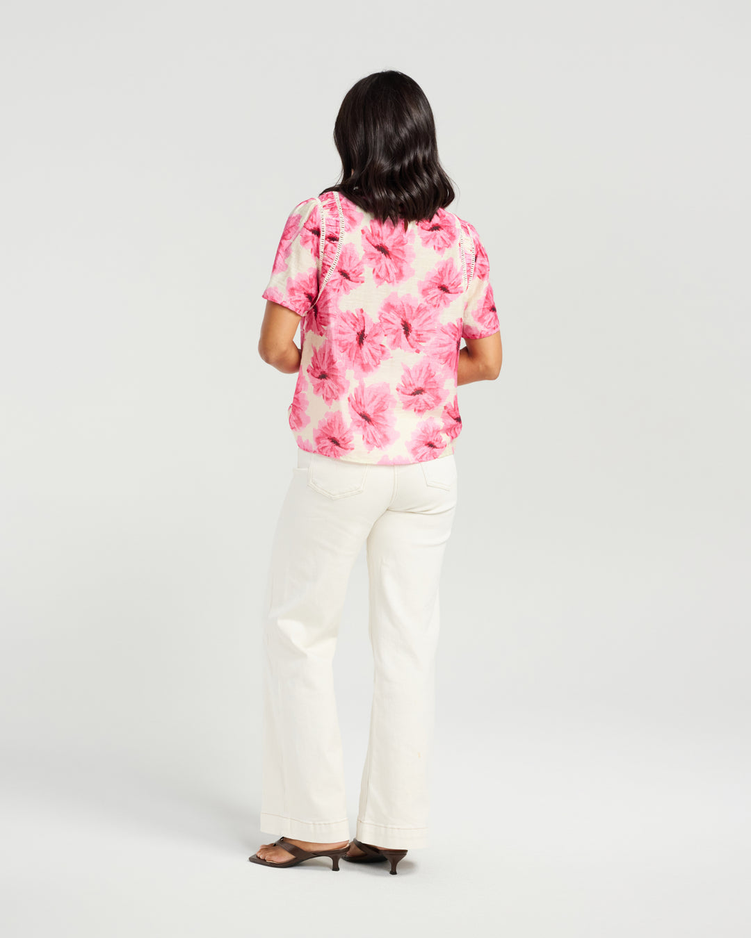 Back view of Kiwi Country Layton Top in Pink Bloom paired with white pants.
