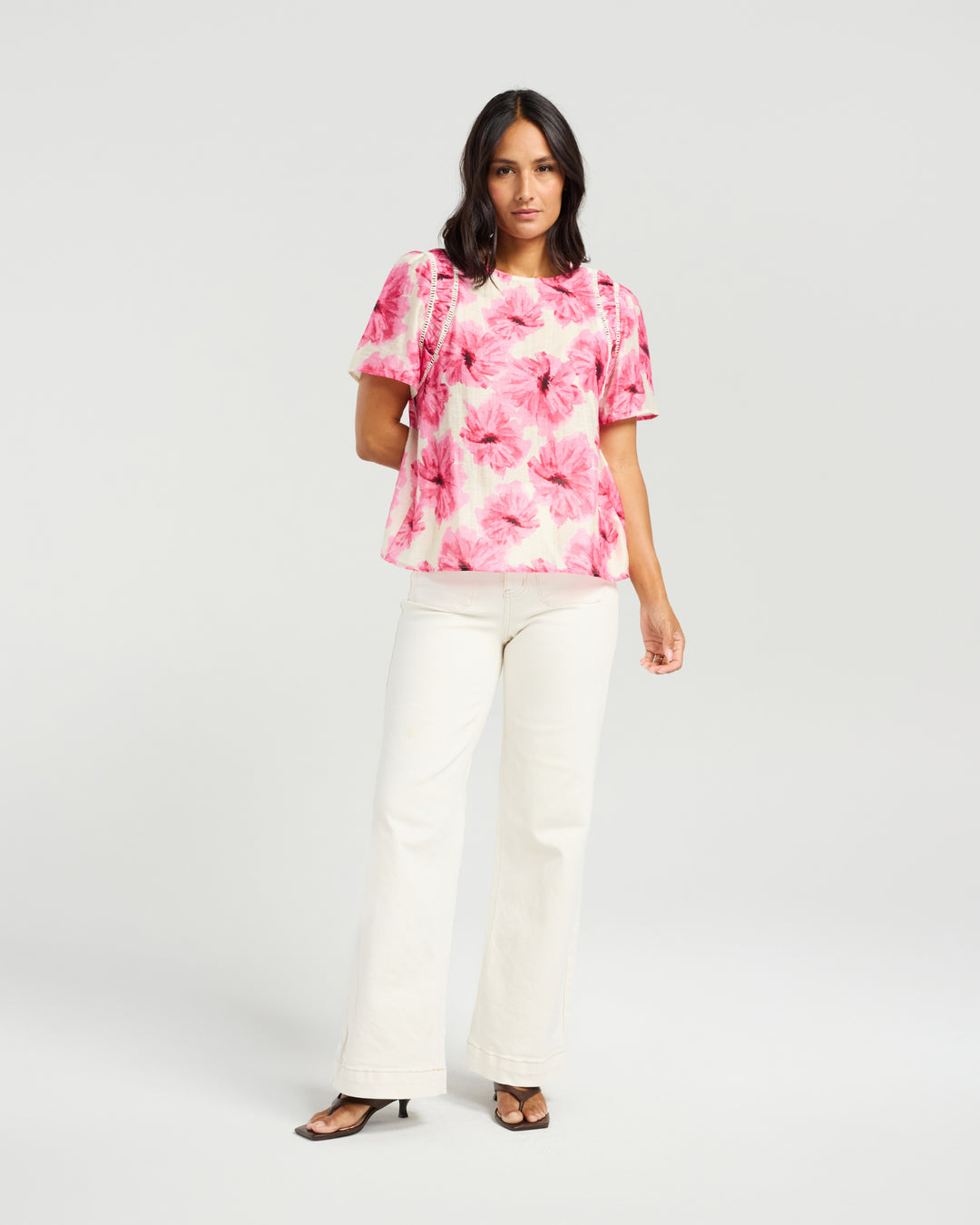 Front view of Kiwi Country Layton Top in Pink Bloom paired with white pants.