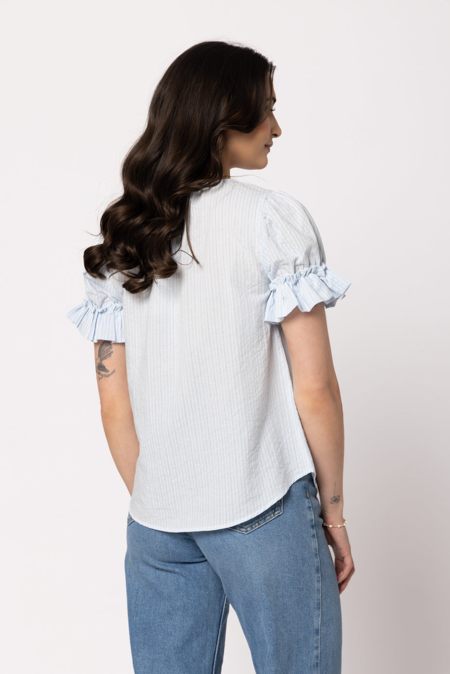 Seeking Lola Vibrant Top in Sky blue striped blouse with ruffle sleeves, back view.